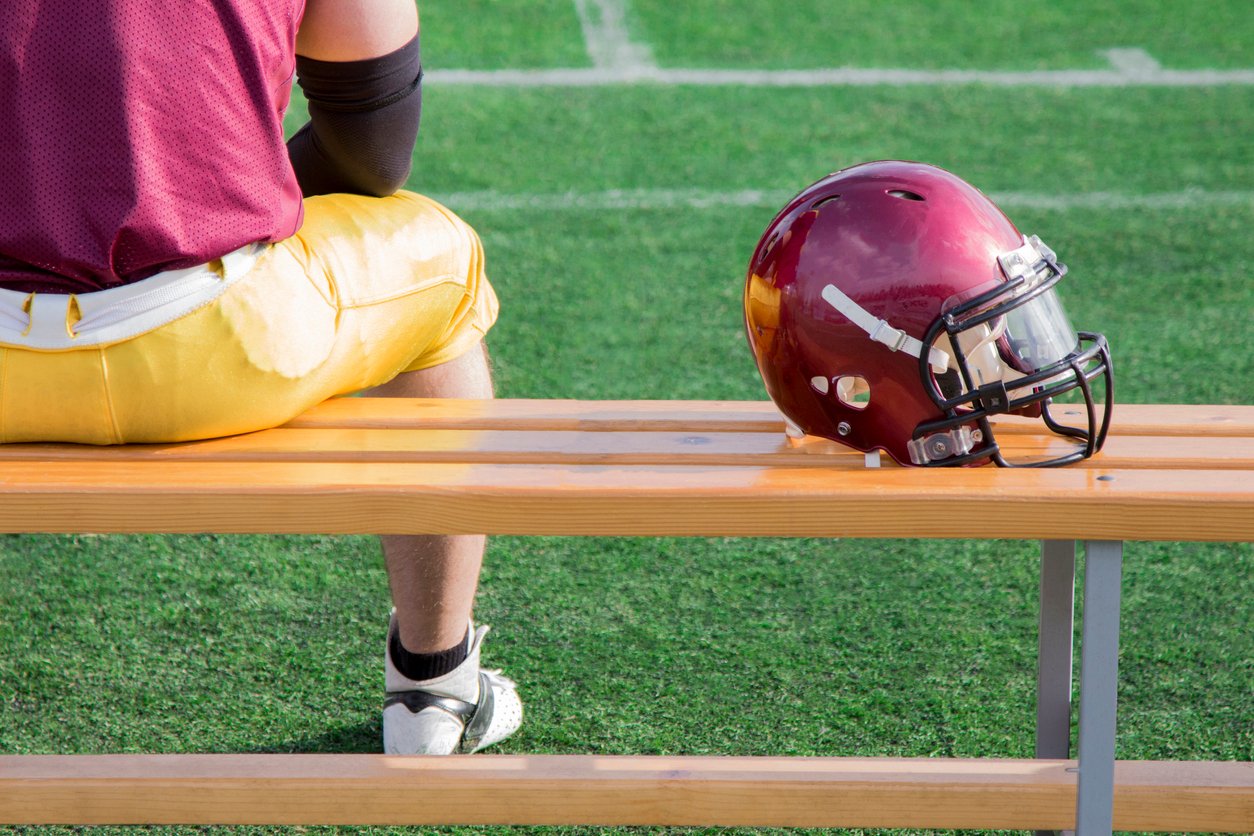 NFL Player along with helmet sitting on bench
