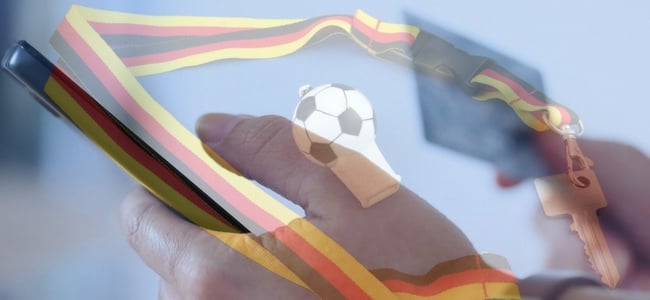 Hand holding phone with german football and whistle in background