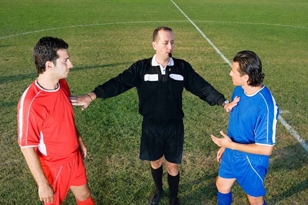 Referee separating two football players