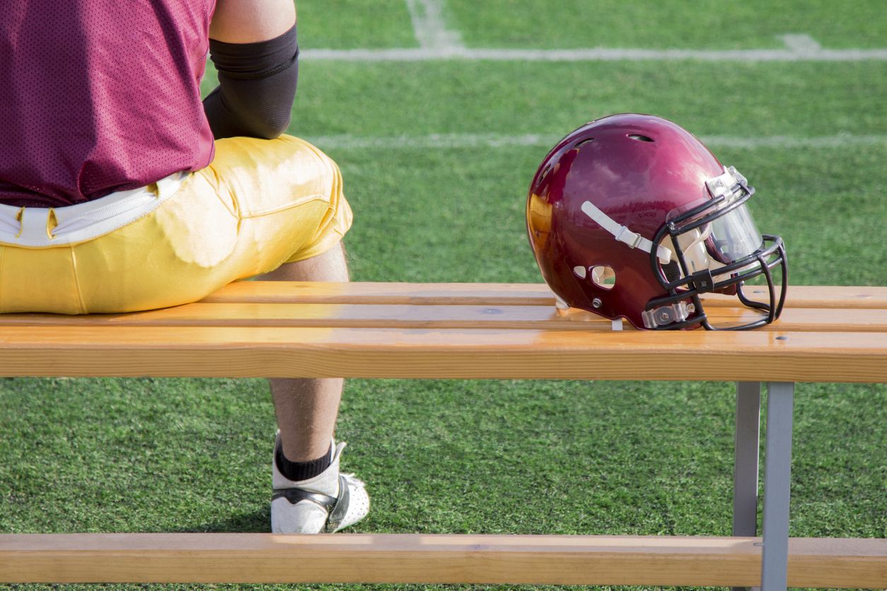 NFL Player along with helmet sitting on bench